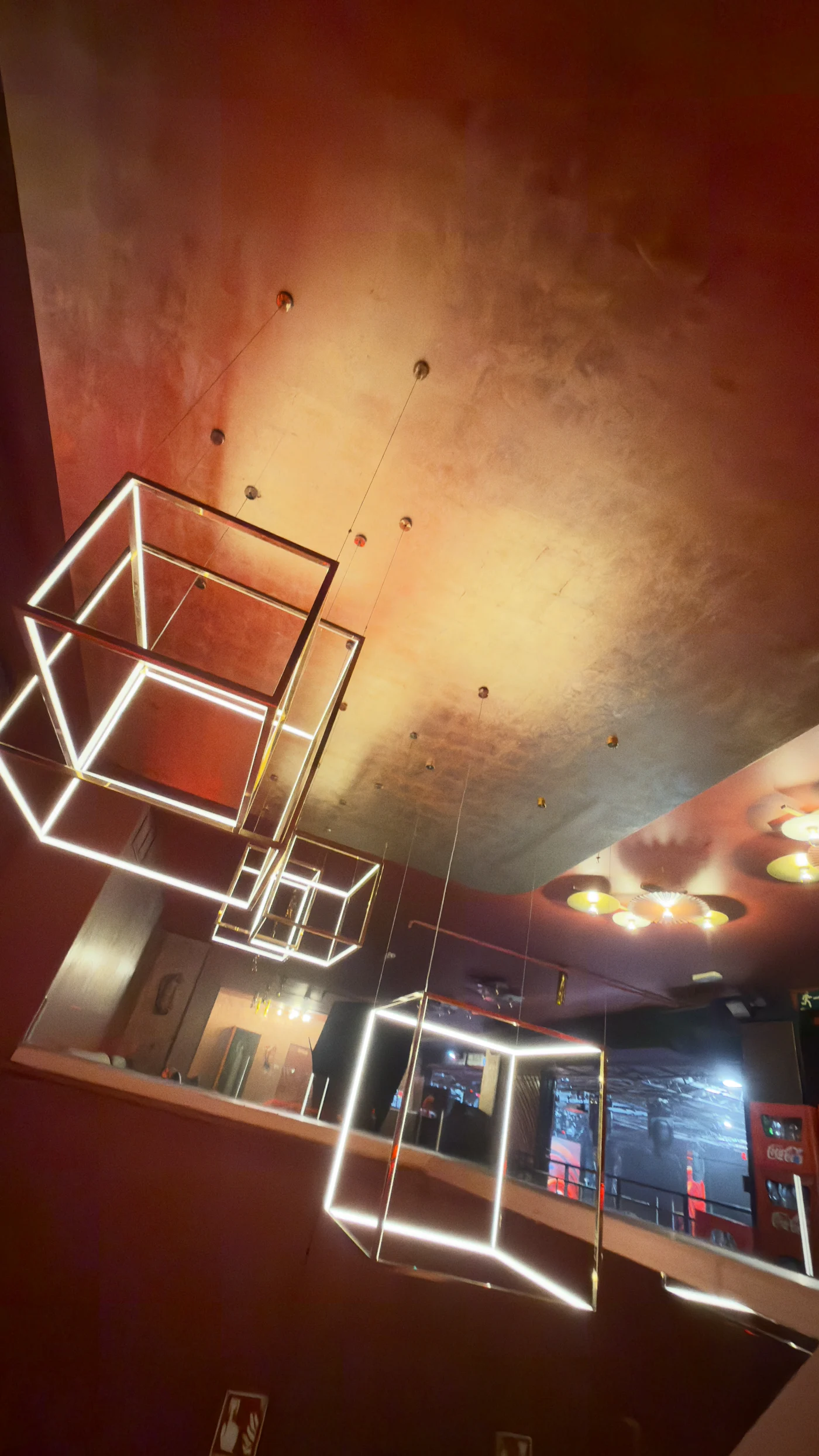 Lámparas cúbicas doradas y techo metalizado en el interior de Sala Chango Madrid.