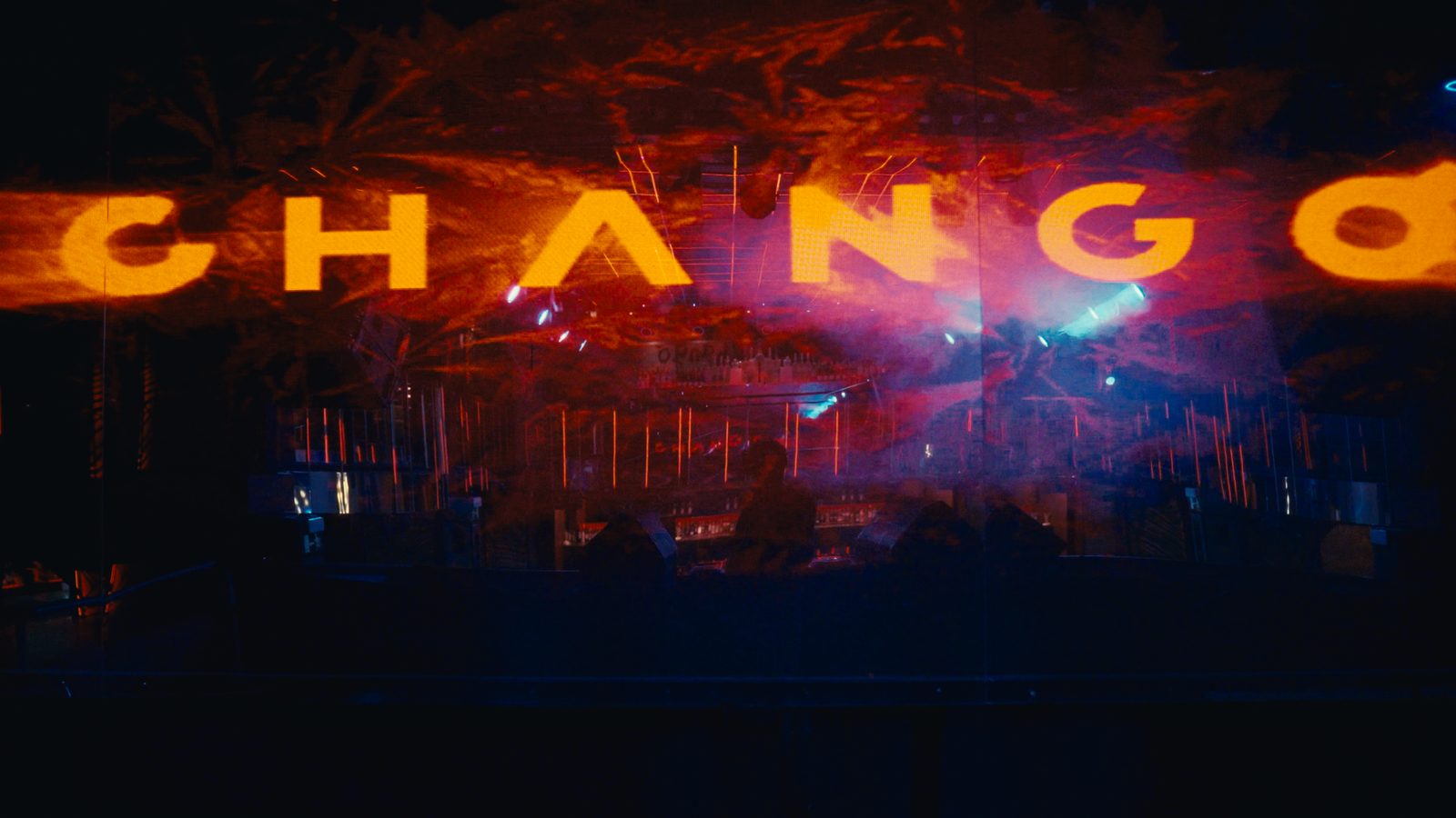 Rótulo luminoso CHANGO en letras naranjas sobre la sala en penumbra.